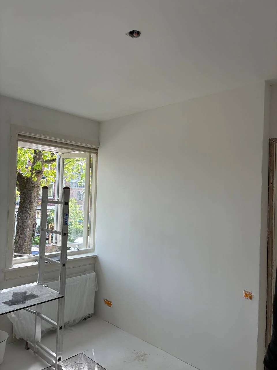 Glad afgewerkte en wit geschilderde gipswand en plafond